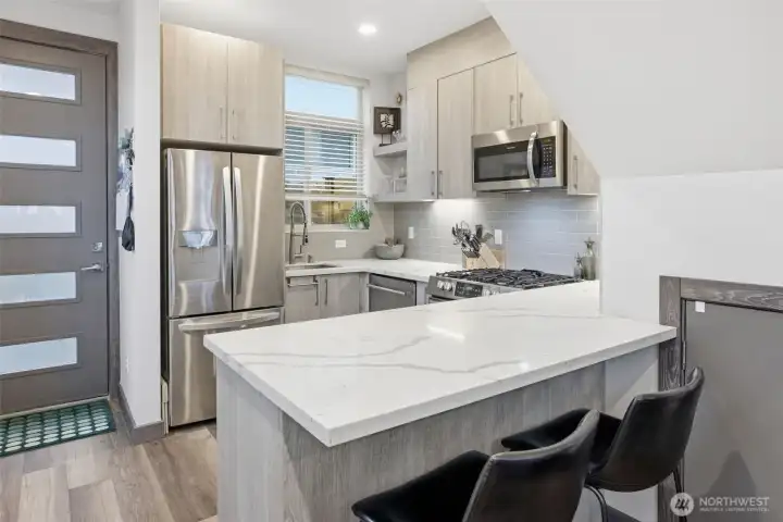 Modern kitchen with quartz countertops, stainless steel appliances, and bar seating for casual dining.