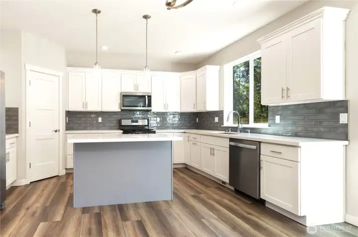 Bright Kitchen with clean lines, and an inviting layout. White cabinetry with soft close features and beautiful tiled backsplash gives it a modern-but-warm balance