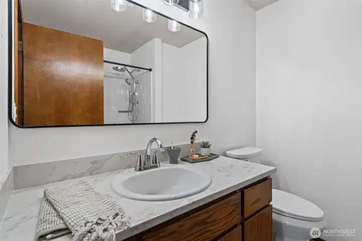 Shared bath features updated finishes along with dual-function rain and handheld shower heads for a spa-inspired touch.