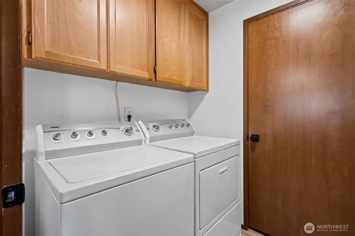 Convenient laundry area opens directly to the attached two-car garage with additional storage shelving.
