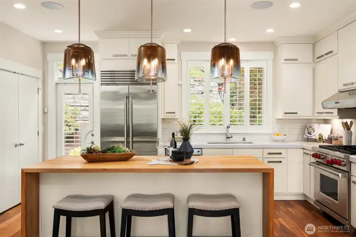 The kitchen was designed to be both the centerpiece of the home and its hardest-working space. A handcrafted butcher block waterfall island, professional Wolf and Sub-Zero appliances, full-height cabinetry, and sculptural glass pendants create a timeless balance of beauty and function. The kitchen was designed to be both the centerpiece of the home and its hardest-working space. A handcrafted butcher block waterfall island, professional Wolf and Sub-Zero appliances, full-height cabinetry, and sculptural glass pendants create a timeless balance of beauty and function.
