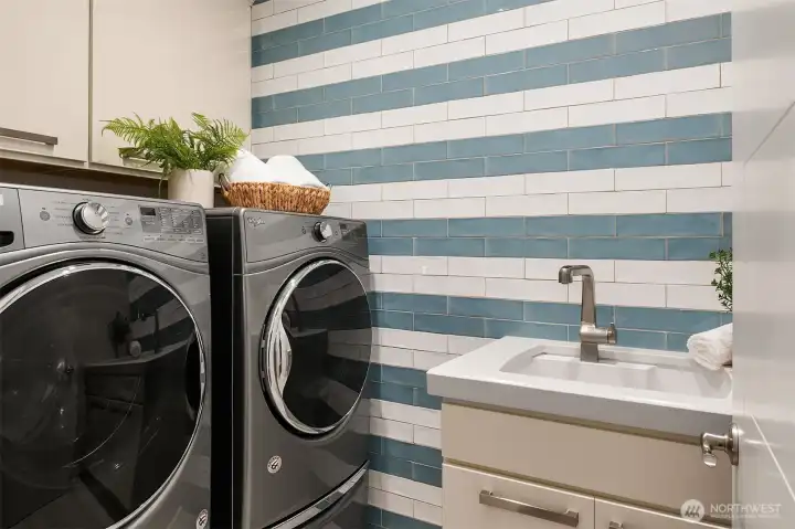 Designed with the same attention to detail found throughout the home, the laundry room features custom cabinetry, quartz countertops, a utility sink, and a handcrafted artisan tile accent wall that brings color, texture, and personality to this beautifully functional space. Designed with the same attention to detail found throughout the home, the laundry room features custom cabinetry, quartz countertops, a utility sink, and a handcrafted artisan tile accent wall that brings color, texture, and personality to this beautifully functional space.