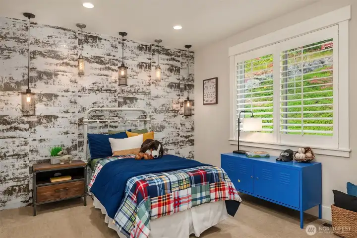 A striking custom feature wall and industrial-inspired pendant lighting create a memorable focal point in this upper-level bedroom, while expansive windows, plush carpeting, and thoughtful finishes provide a bright, comfortable retreat with timeless appeal. A striking custom feature wall and industrial-inspired pendant lighting create a memorable focal point in this upper-level bedroom, while expansive windows, plush carpeting, and thoughtful finishes provide a bright, comfortable retreat with timeless appeal.