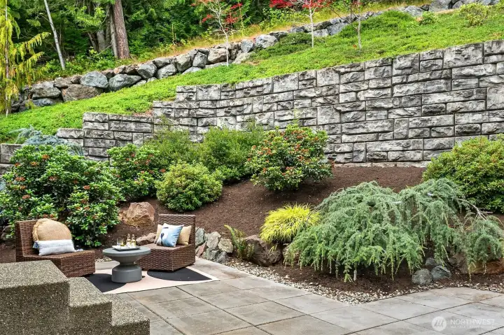 Beautifully landscaped and exceptionally private, the fully fenced backyard is anchored by an expansive entertaining patio and framed by impressive terraced stone retaining walls, curated plantings, and a lush evergreen backdrop that offers year-round serenity. Beautifully landscaped and exceptionally private, the fully fenced backyard is anchored by an expansive entertaining patio and framed by impressive terraced stone retaining walls, curated plantings, and a lush evergreen backdrop that offers year-round serenity.