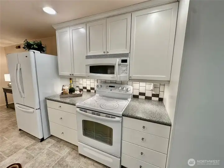 Close-up view of the range/oven, microwave and tile back-splash. Close-up view of the range/oven, microwave and tile back-splash.