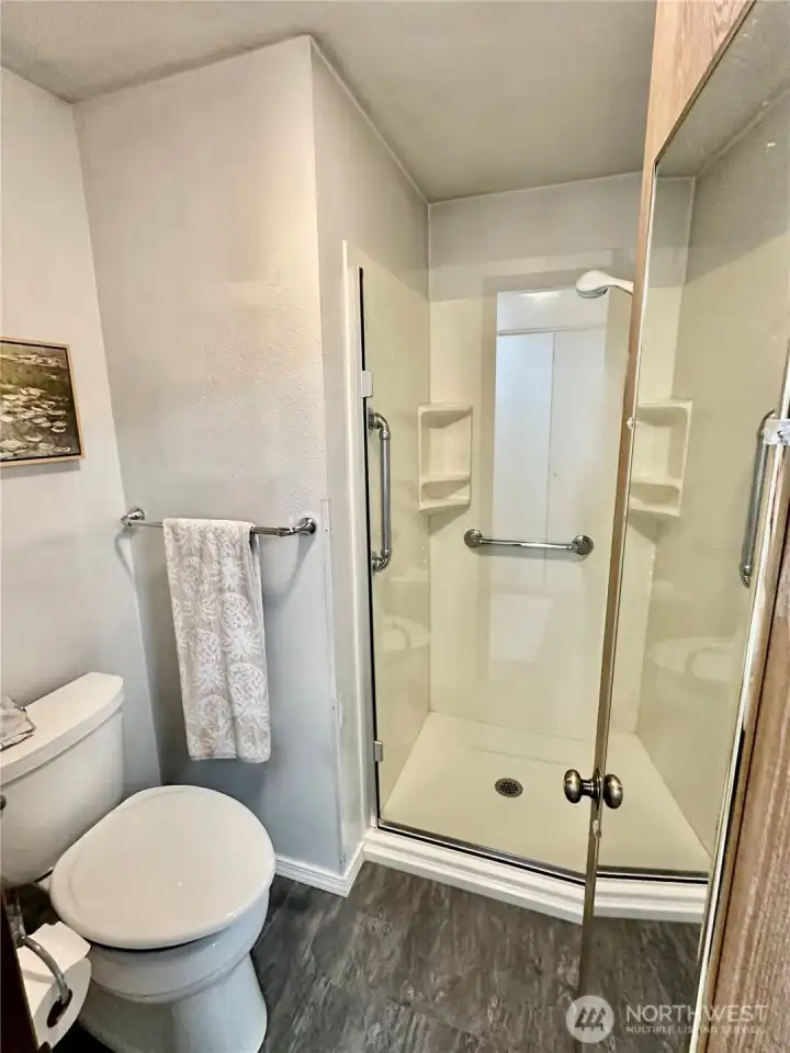 Primary commode and shower stall with glass door. Primary commode and shower stall with glass door.