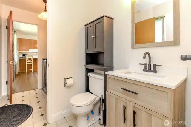 From primary bedroom looking into 1/2 bath with door leading into utility room and further into dining area.