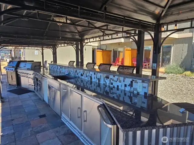 The outdoor kitchen with 2 BBQs, 2 mini fridges, a sink and 14 foot bar provide everything needed for a get together rain or shine.