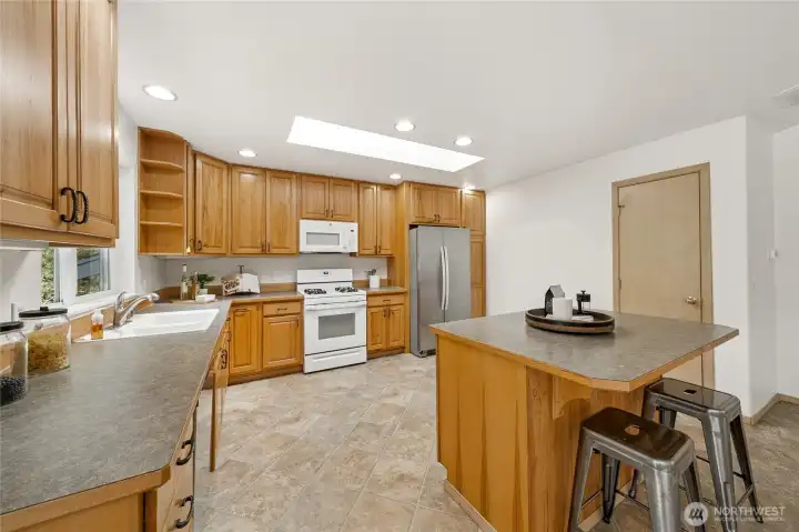 Expansive kitchen with central island, stylish wood cabinetry, and new microwave & dishwasher.
