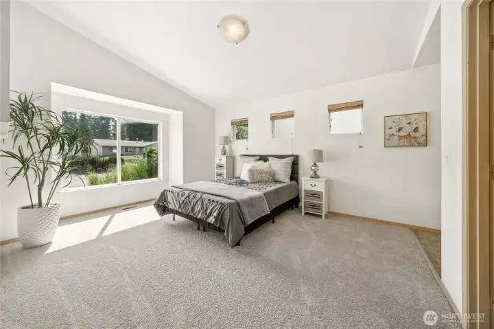 Dreamy and spacious primary bedroom with vaulted angled ceiling.