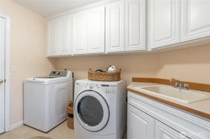 Ample laundry room space conveniently located off of garage entrance. Lots of storage and large sink.   Appliances convey with home.
