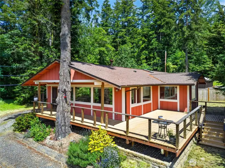 Tucked among towering evergreens, this charming retreat offers warm Northwest character, expansive wraparound decking, and a peaceful setting that invites year-round outdoor living.