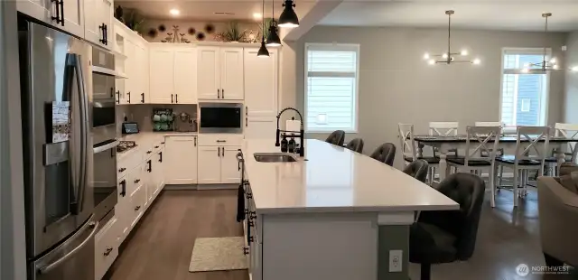 View of the Huge Great Room Island Kitchen showing all Vinyl Plank Flooring,White Cabinets, Freshly Painted Through Out, Dining Room and Partial Living Room.