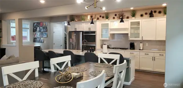 VAnother view of the Huge Great Room Island Kitchen showing all Vinyl Plank Flooring,White Cabinets, all Stainless Appliances including Double Oven, Freshly Painted Through Out,  and Partial Dining Room.