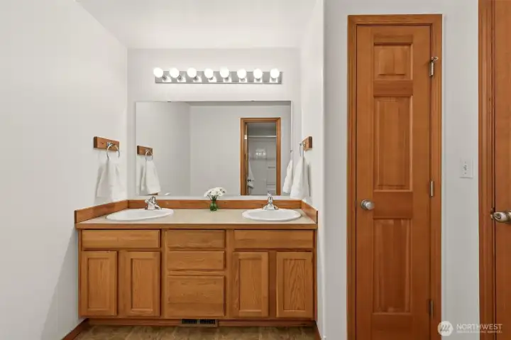 Full Bathroom next to other bedrooms with dual sinks and closed space for the bath/shower/toilet within the bathroom.
