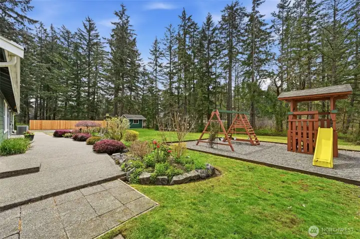 Expansive Patio and Backyard with very own playground and nicely wooded backdrop.