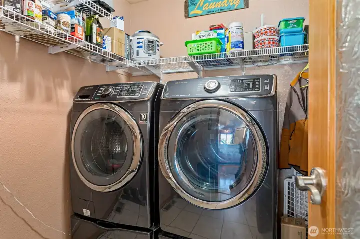 Laundry room conveniently located off the kitchen with extra storage space and overhead shelving.