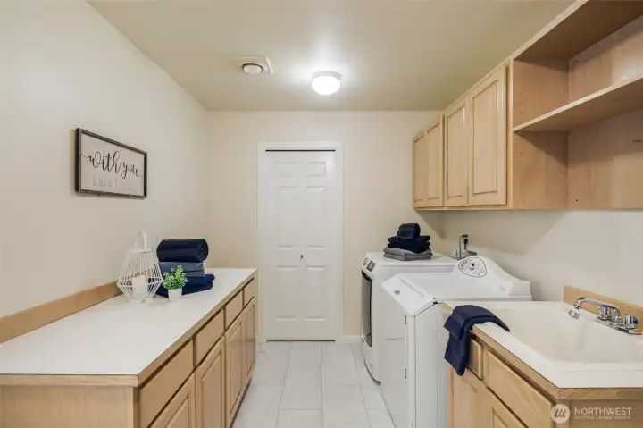 Utility room off the garage with loads of counter space, new flooring, a large laundry sink and lots of cabinet space.  The washer and dryer stay!