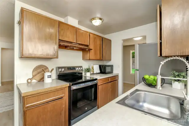 Kitchen has new stove, refrigerator, dishwasher, sink.