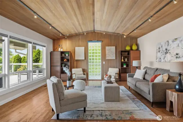 The expansive and inviting living room stuns with newly installed hardwoods, cedar-lined vaulted ceilings, and walls of windows framing the view—yes, even electronic blinds!