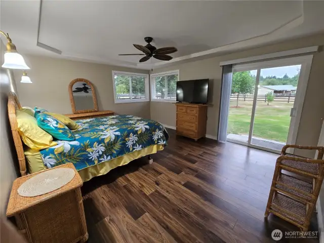 Spacious primary bedroom with walk in closet, coffered ceiling, ceiling fan and sliding doors to back yard.