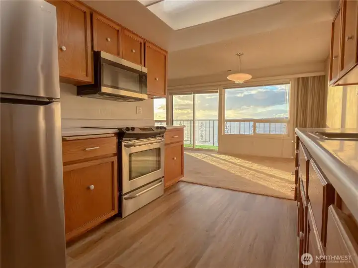 Spacious galley kitchen with a new refrigerator and microwave.