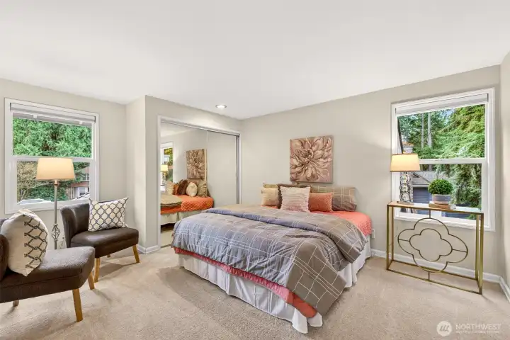 One of the secondary bedrooms offers a calm, leafy outlook from dual windows, mirrored closet doors, and fresh carpet for a clean, move in ready feel.