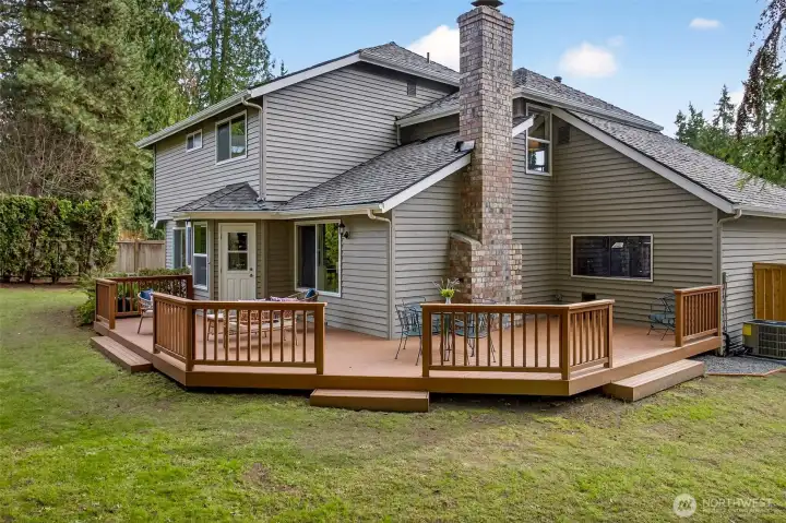 Rear exterior view showcases the large entertaining deck, a spacious yard, and the benefit of a new roof, all framed by tall evergreens for a classic English Hill setting.