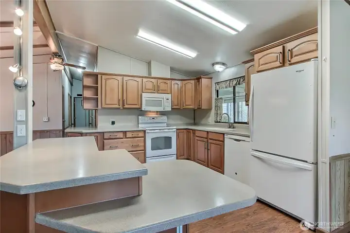 View of your remodeled kitchen! Custom cabinetry, solid-surface countertops, plenty of lighting. I love the 2-tiered counter for ease of gathering and entertaining, and all appliances are included!