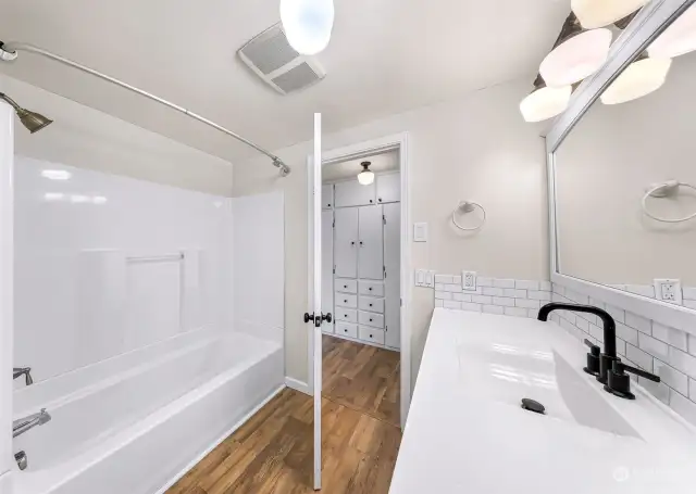 Primary Bathroom with linen shelves to the left of the bath/shower.