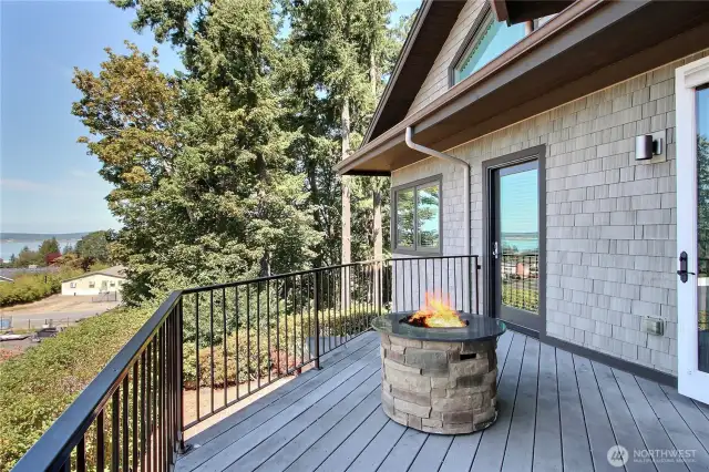 View of the balcony/deck off of the main floor family room and also main floor bedroom with cozy firepit. Views for days!