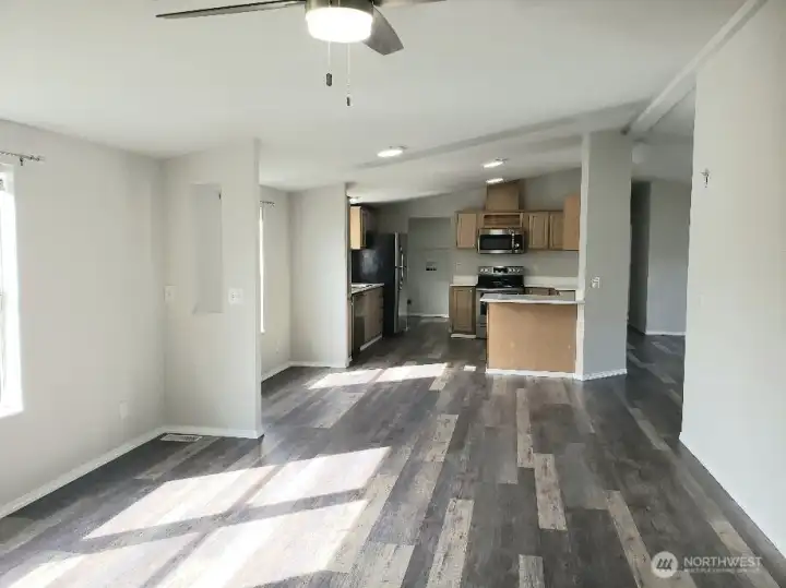 Another Opposite View Picture of the Huge Kitchen Showing Ample Cabinet Space, Newer Counter Tops, LED Lighting, All Stainless Appliances Including Built In Microwave, Glass Top Stove Oven, Trim, and Vinyl Plank Flooring Looking into the Kitchen And Ding Room from the Second Living Room.