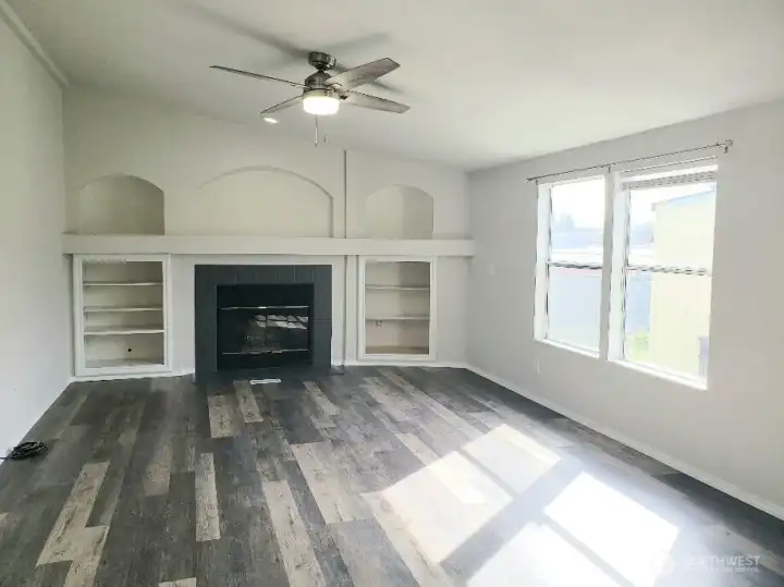 Picture of the Spacious Second Living Room with a Wood Burning Fireplace, Mantle and Cabinet Surround. Newer  Trim, and Vinyl Plank Flooring Looking from the Dining Room.