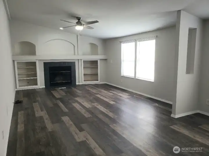 Another Picture of the Spacious Second Living Room with a Wood Burning Fireplace, Mantle and Cabinet Surround. Newer  Trim, and Vinyl Plank Flooring Looking from the Dining Room.