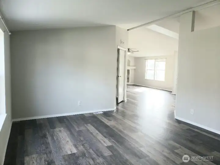 Picture of the Enormous Main Living Room from the the From the Front Entry Door Showing the Vinyl Plank Flooring and Newer Paint and Trim Looking at the Second Living Area and the Primary Bedroom.