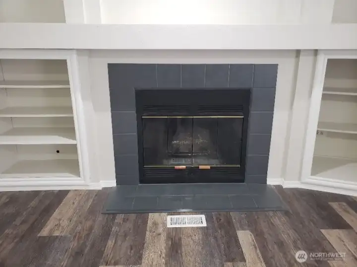 Another Close up Picture of the Spacious Second Living Room with a Wood Burning Fireplace, Mantle and Cabinet Surround. Newer  Trim, and Vinyl Plank Flooring.