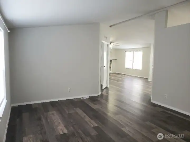 Picture of the Enormous Main Living Room from the the From the Front Entry Door Showing the Vinyl Plank Flooring and Newer Paint and Trim Looking at the Second Living Area and the Primary Bedroom.