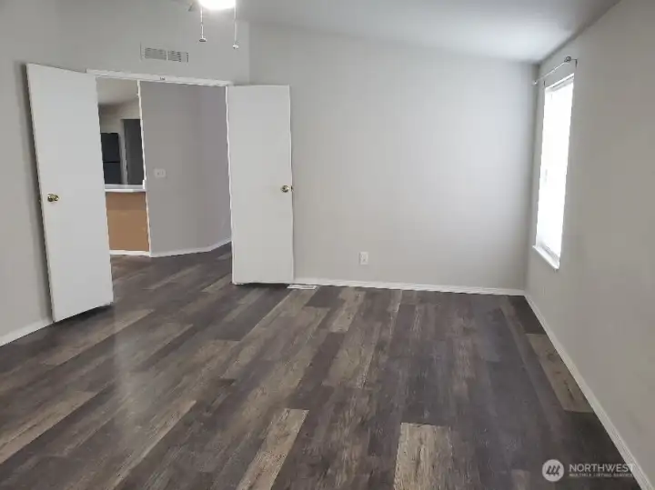 Another View of the Picture Huge Primary Master Bedroom with Double Entry Doors open with Newer Trim, and Vinyl Plank Flooring.