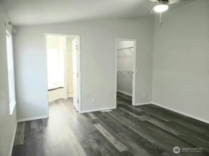 Another View of the Huge Primary Master Bedroom from the Double Entry Doors Showing Newer Trim, and Vinyl Plank Flooring and Looking at the Primary Bath Room and Walk In Closet.