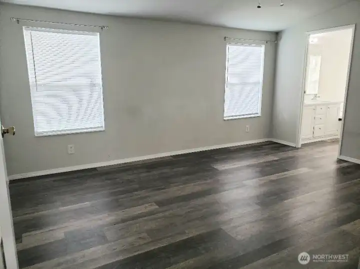 Another Opposite View of the Huge Primary Master Bedroom from the Double Entry Doors Showing Newer Trim, and Vinyl Plank Flooring and Looking at the Primary Bath Room and Walk In Closet.