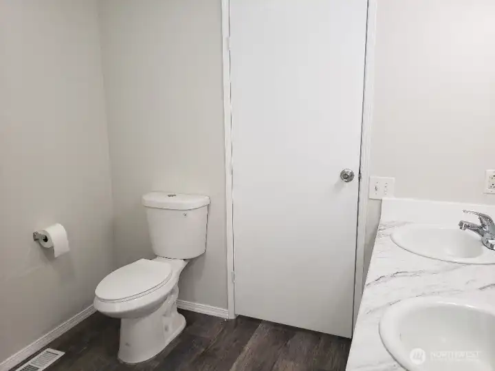 Another Picture of the Huge Primary Master Bathroom with Newer Toilet, Newer Trim, and Vinyl Plank Flooring.