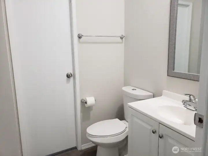 A View of the Main Guest Bathroom with Newer Sink Vanity, Toilet, Newer Trim, and Vinyl Plank Flooring.