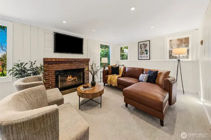 Daylight lower-level living room with fireplace. Fresh paint & carpet! To the right find a bedroom, den/office, additional laundry & full bathroom.