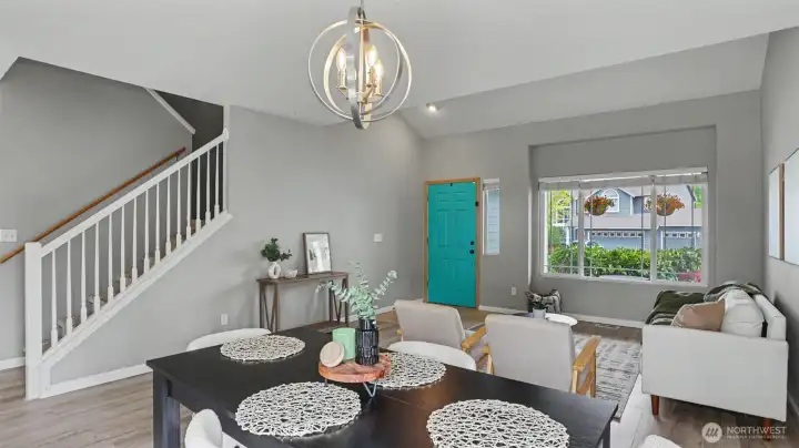 Light-filled dining and living area featuring modern fixtures, stylish vaulted ceilings, and a bold, welcoming entryway