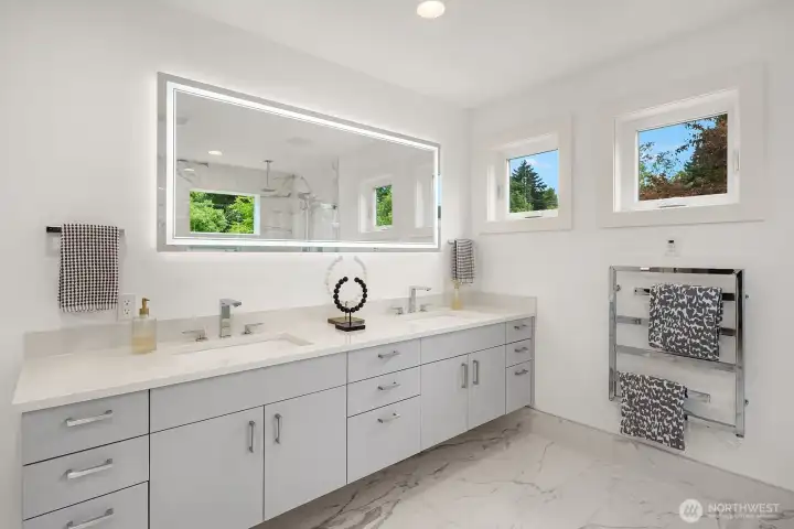 Upper-level primary bathroom - dual sinks, heated floors, lighted mirror, and towel warmer