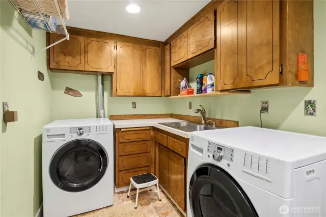 Fully-equipped laundry room with lots of cupboards, hanging space and laundry sink