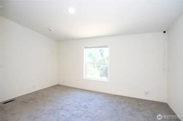 Guest Suite #1 features a vaulted ceiling and a bright window, making this room warm and inviting.