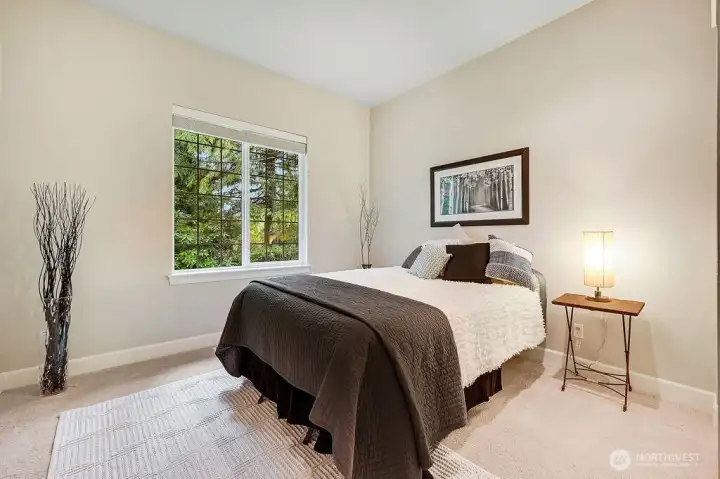 A comfortable guest bedroom that feels private and serene, with a window looking out onto the lush, natural surroundings.
