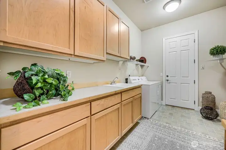 Functional and well-organized, this laundry room features ample storage, generous countertops, and easy entry to the garage.