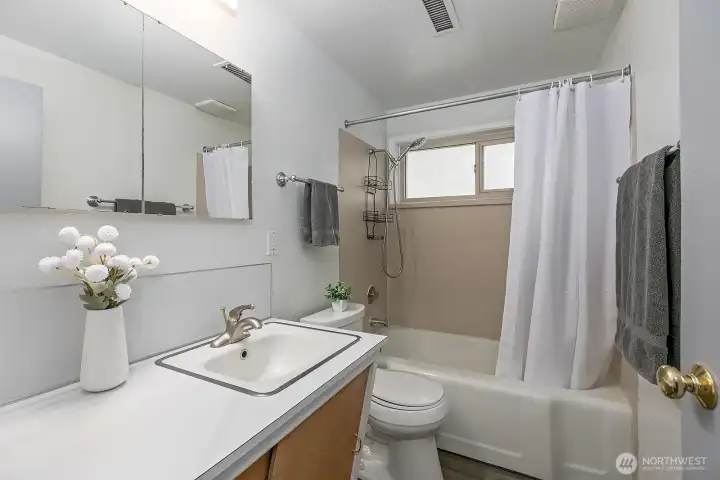 Full bath with mid-century vanity, new paint and flooring.